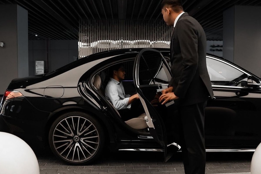 Chauffeur en costume ouvrant la portière d'une berline noire